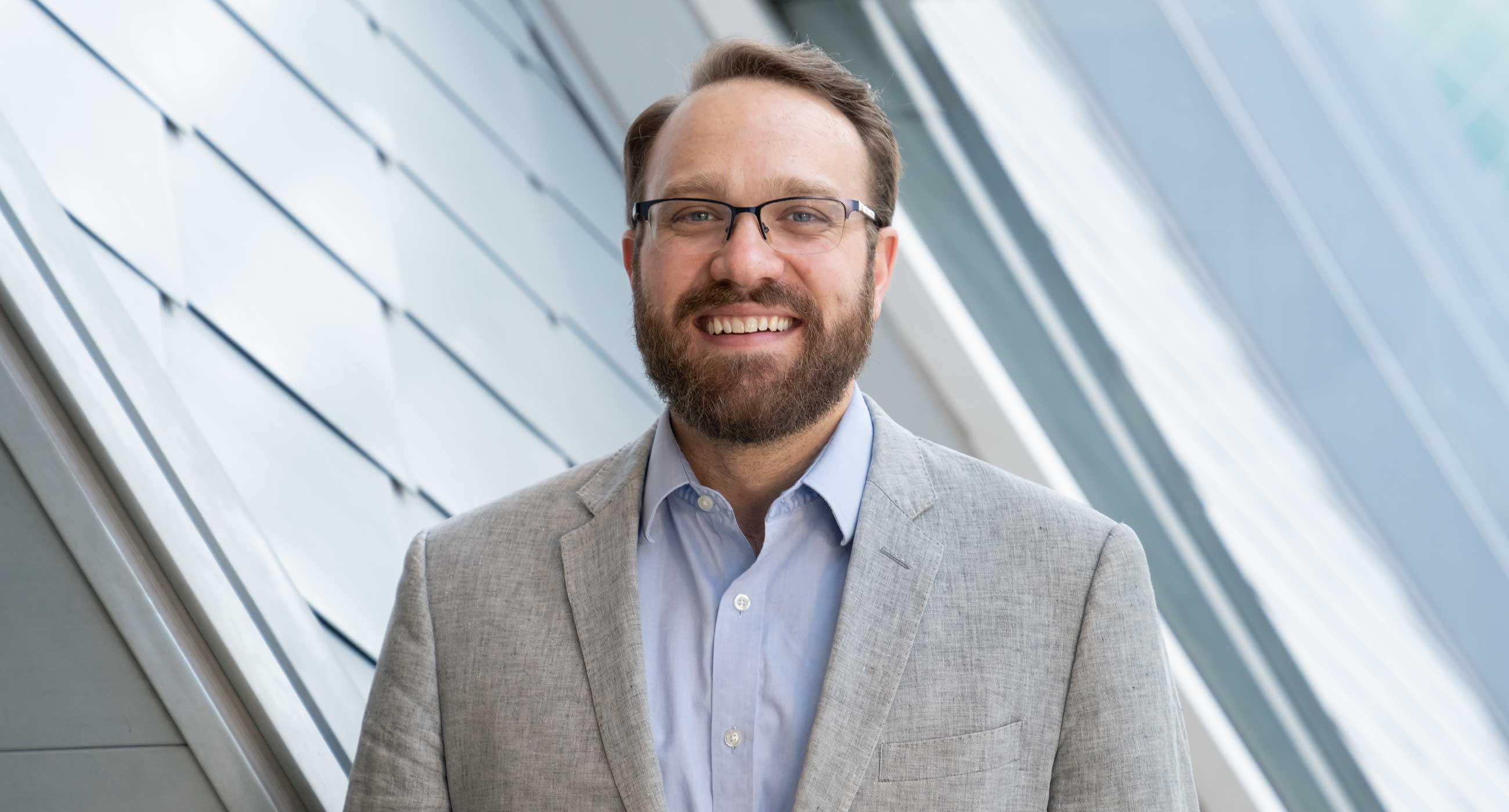 Andrew Schultz smiling in front of a window.