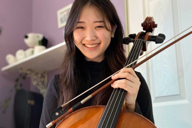 Mei Hotta holding a cello and smiling