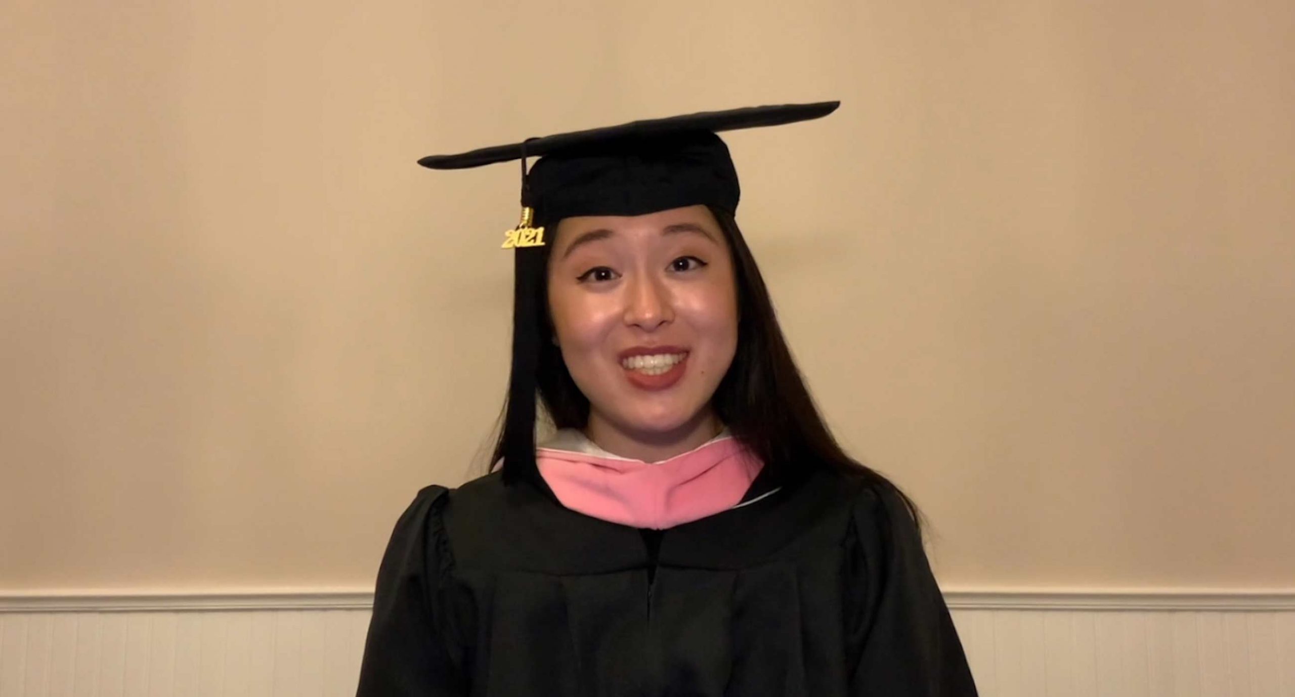 Alyssa Katahara wearing cap and gown with pink stole smiling
