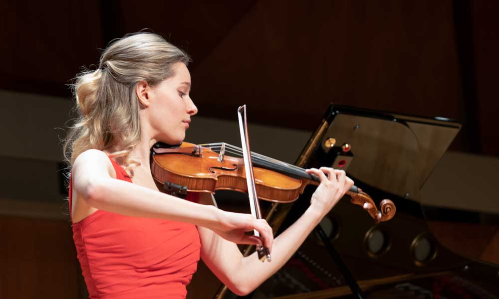 Violinist wearing a red dress playing on stage
