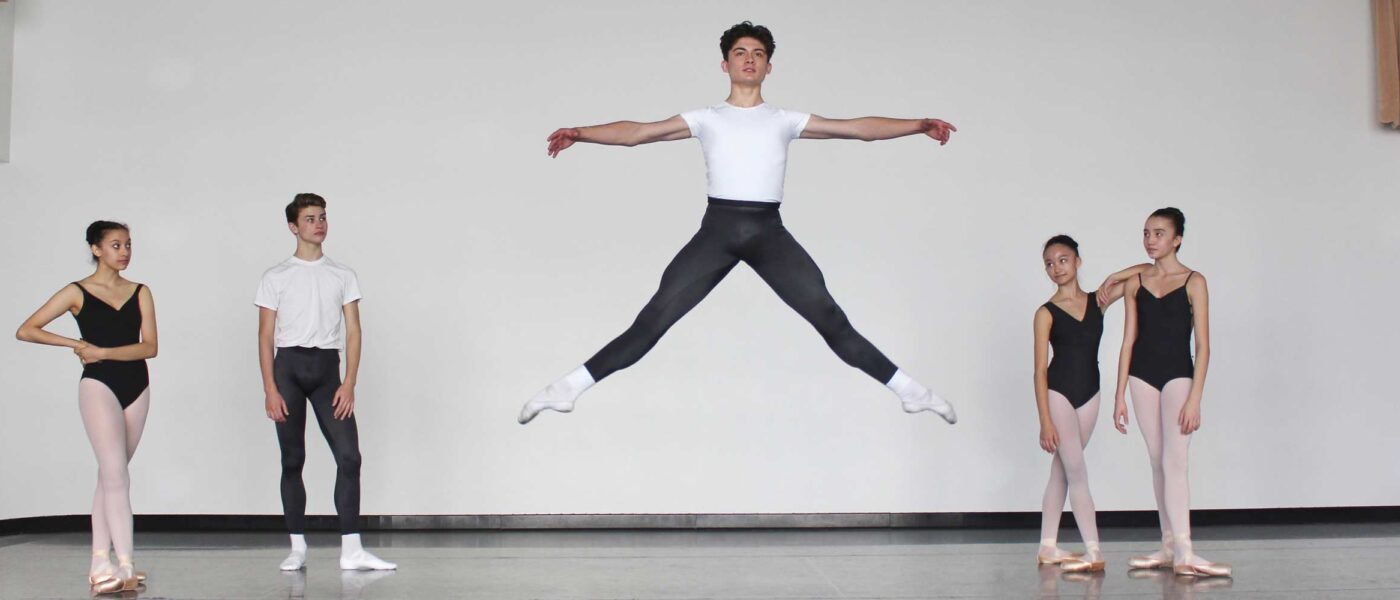 Male dancer jumping and posing with two dancers standing on either side