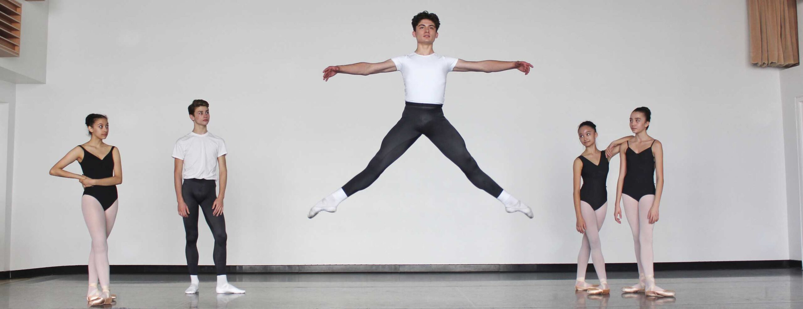 Male dancer jumping and posing with two dancers standing on either side