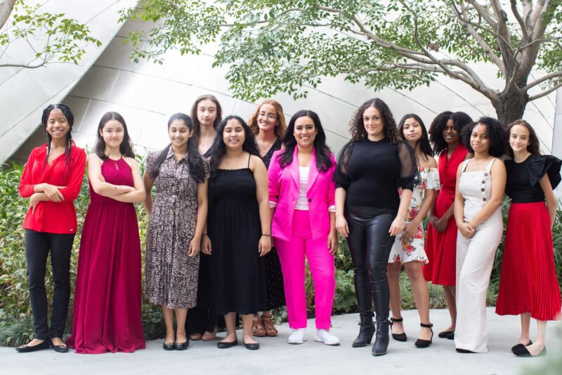 2021 Fortissima cohort wearing red, pink, and white outside with trees in background